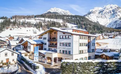 a hotel with snow covered mountains in the background at Sporthotel Exclusive in San Vigilio Di Marebbe