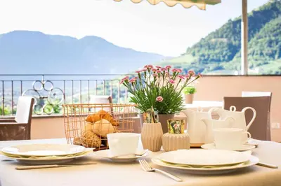 a table with plates and utensils and flowers on it at Pension An Der Linde in Lagundo