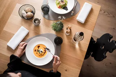 a person sitting at a table with a plate of food at Alpinhotel Vajolet - Adults only in Tires