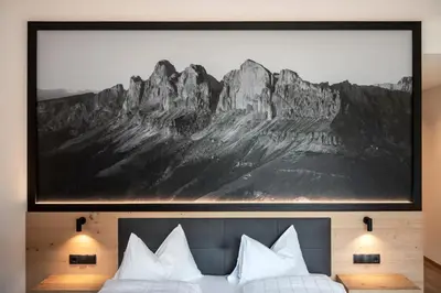 a bedroom with a painting above a bed with white pillows at Alpinhotel Vajolet - Adults only in Tires