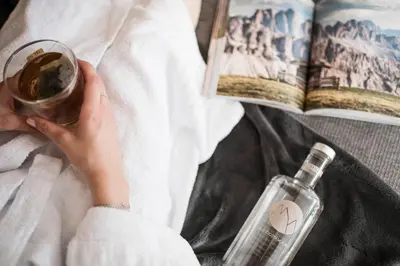 a woman holding a glass of wine and a book and a bottle at Alpinhotel Vajolet - Adults only in Tires