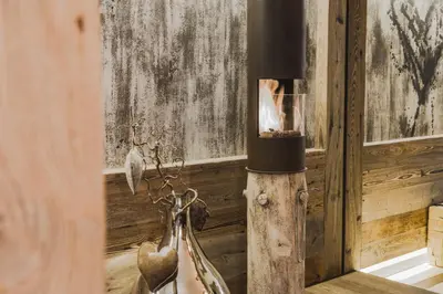 a fireplace in a room with a wooden wall at Hotel Chalet S - Dolomites Design - adults recommended in Selva di Val Gardena