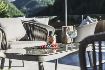 a table with a wine glass and fruit on a patio at Hotel Chalet S - Dolomites Design - adults recommended in Selva di Val Gardena