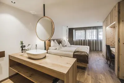 a bedroom with a bed and a mirror on a table at Hotel Chalet S - Dolomites Design - adults recommended in Selva di Val Gardena
