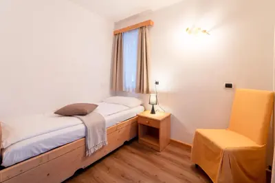 a bedroom with a bed and a desk and a television at Negritella Sweet Hotel in Ziano di Fiemme