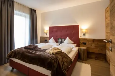 a bedroom with a large bed with a red headboard at La Bercia Alpine Lodge & Spa in La Villa