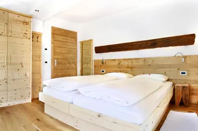 two beds in a bedroom with wooden walls at La Bercia Alpine Lodge & Spa in La Villa