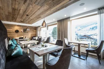 a restaurant with tables and chairs and a large window at La Bercia Alpine Lodge & Spa in La Villa