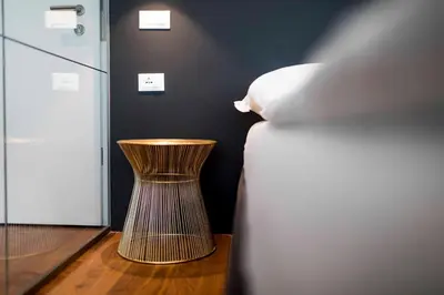 a bedroom with a bed and a stool next to a pillow at Stay COOPER l MAVIK Loft & Apartment in Bolzano