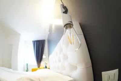 a light hanging over a bed in a room at Stay COOPER l MAVIK Loft & Apartment in Bolzano