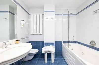 a bathroom with a sink and a tub and a toilet at Chalet Barbara in Arabba