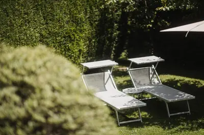 three chairs and a picnic table with an umbrella at Hotel Garni Andrianerhof in Andrian