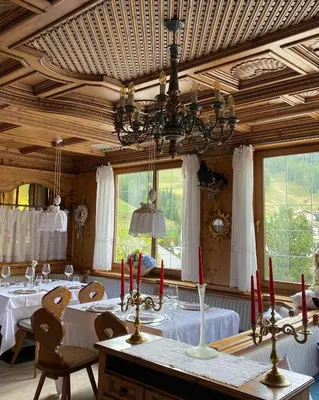 a dining room with two tables and a chandelier at Sporthotel Arabba in Arabba