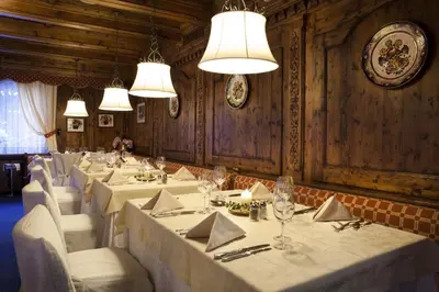 a dining room with white tables and chairs and lights at Sporthotel Arabba in Arabba