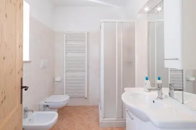 a white bathroom with a sink and a toilet at La Piccola Casa Verde in Canale San Bovo