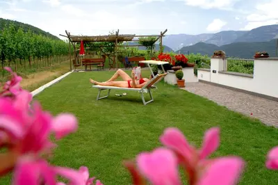 a woman laying in lounge chairs on a lawn at Residence Nesslerheim in Termeno