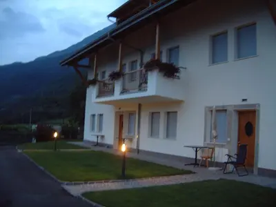a large white building with a table in the yard at Residence Nesslerheim in Termeno