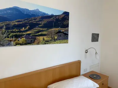 a picture hanging on a wall above a bed at Residence Nesslerheim in Termeno