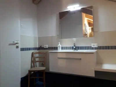 a bathroom with a sink and a mirror and a chair at HartlHof in Proves