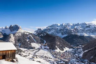 a view of a snowy mountain range with a building at Hotel Garni Concordia - Dolomites Home in Selva di Val Gardena