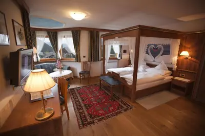 a bedroom with a canopy bed and a television at Hotel Garni Concordia - Dolomites Home in Selva di Val Gardena