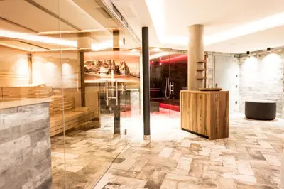 a lobby with a glass wall and a table at Hotel Pinei in Ortisei
