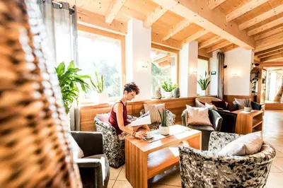 a man working on a laptop in a restaurant at Hotel Pinei in Ortisei