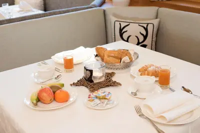 a table with a breakfast of bread and fruit on it at Hotel Pinei in Ortisei