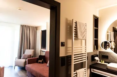 a room with a living room with a couch and a mirror at Hotel Pinei in Ortisei