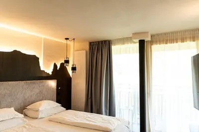 a bedroom with a bed and a large window at Hotel Pinei in Ortisei