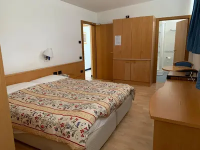 a bedroom with a bed and a dresser at Garni Enrosadira in Vigo di Fassa