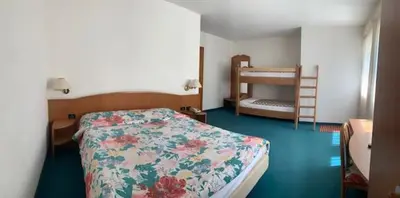 a bedroom with a bed with a floral bedspread at Garni Enrosadira in Vigo di Fassa