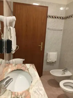 a bathroom with a sink and a toilet and a door at Garni Enrosadira in Vigo di Fassa