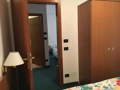 a bedroom with a door open to a room with a bed at Garni Enrosadira in Vigo di Fassa