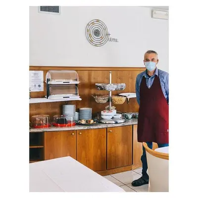 a man standing in a kitchen wearing a mask at Garni Enrosadira in Vigo di Fassa