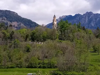 a building with a clock tower in the middle of a field at Casa Tiziana By Go New Location in Carano