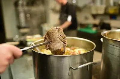 a piece of meat is being held in a pot of food at Hotel Gasthof Jochele in Falzes