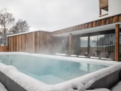 a swimming pool in a snow covered house at Hotel Gasthof Jochele in Falzes