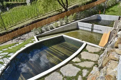 a pool of water in a garden next to a fence at Residence Blumenthalerhof in Lagundo