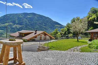 a stone table in front of a house with a mountain at Residence Blumenthalerhof in Lagundo