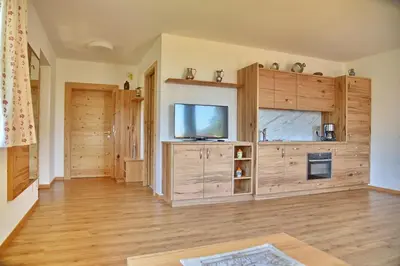 a living room with wooden floors and a flat screen tv at Residence Blumenthalerhof in Lagundo