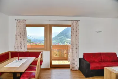a living room with a red couch and a table at Residence Blumenthalerhof in Lagundo