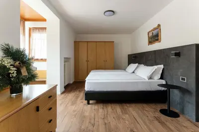 a bedroom with a large bed and a wooden floor at Best Western Hotel Nevada in San Vito di Cadore