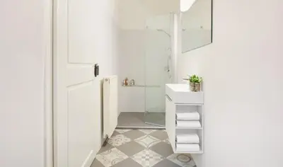 a white bathroom with a shower and a sink at Arcade Apartments in Bolzano