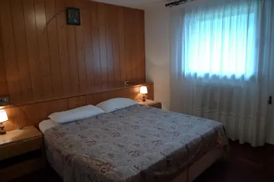 a bedroom with a bed and a window and two lamps at Condominio Le Marmotte in Selva di Cadore
