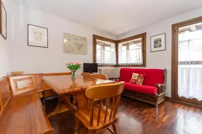 a living room with a table and a red couch at Condominio Le Marmotte in Selva di Cadore