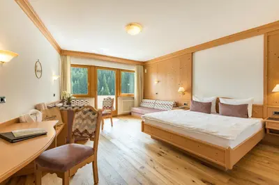 a bedroom with a bed and a desk and chairs at Hotel Christoph in Valdaora