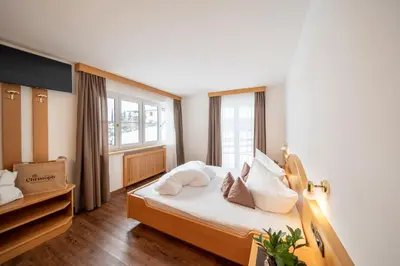 a bedroom with a bed with white sheets and pillows at Hotel Christoph in Valdaora