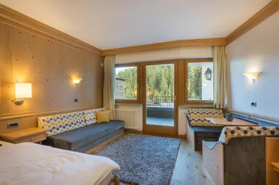 a hotel room with a bed and a couch and a table at Hotel Christoph in Valdaora