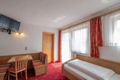 a hotel room with a bed and a desk and a table at Residence Mühlegg in Valdaora